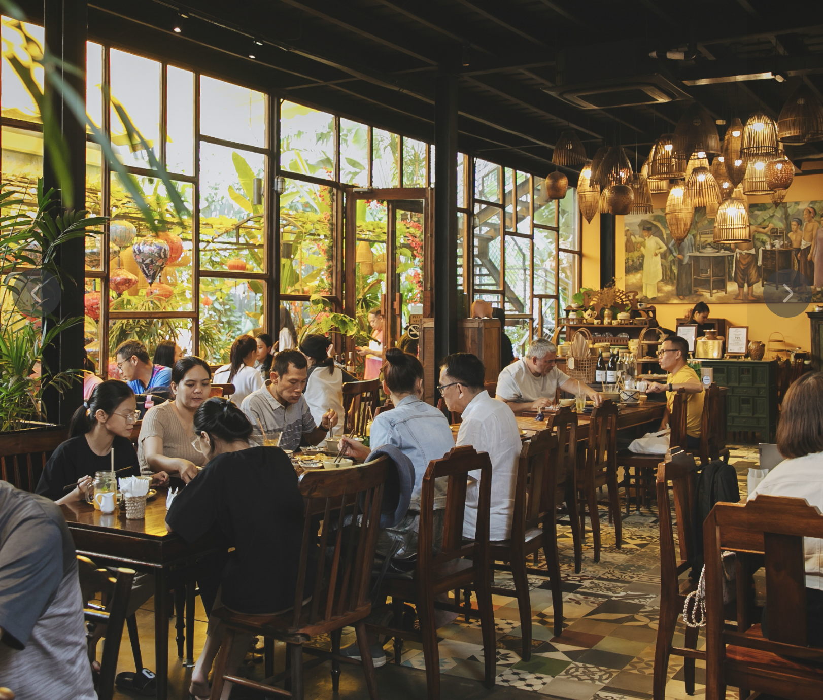 Interior of Quán Bụi with patterned tile floor, wooden chairs, and rattan pendants
